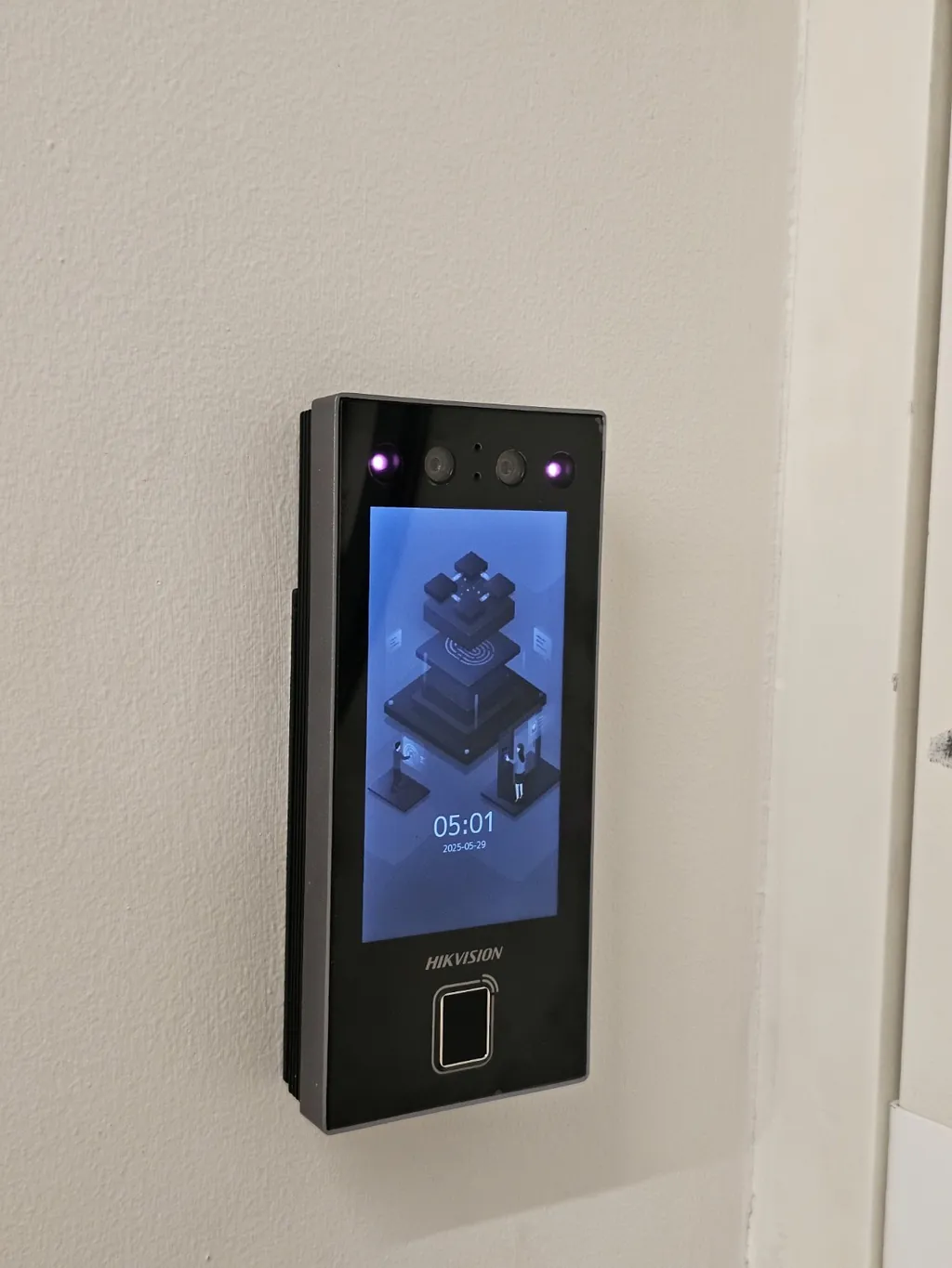 Terminal de control de acceso Hikvision instalado en una pared, con la pantalla encendida