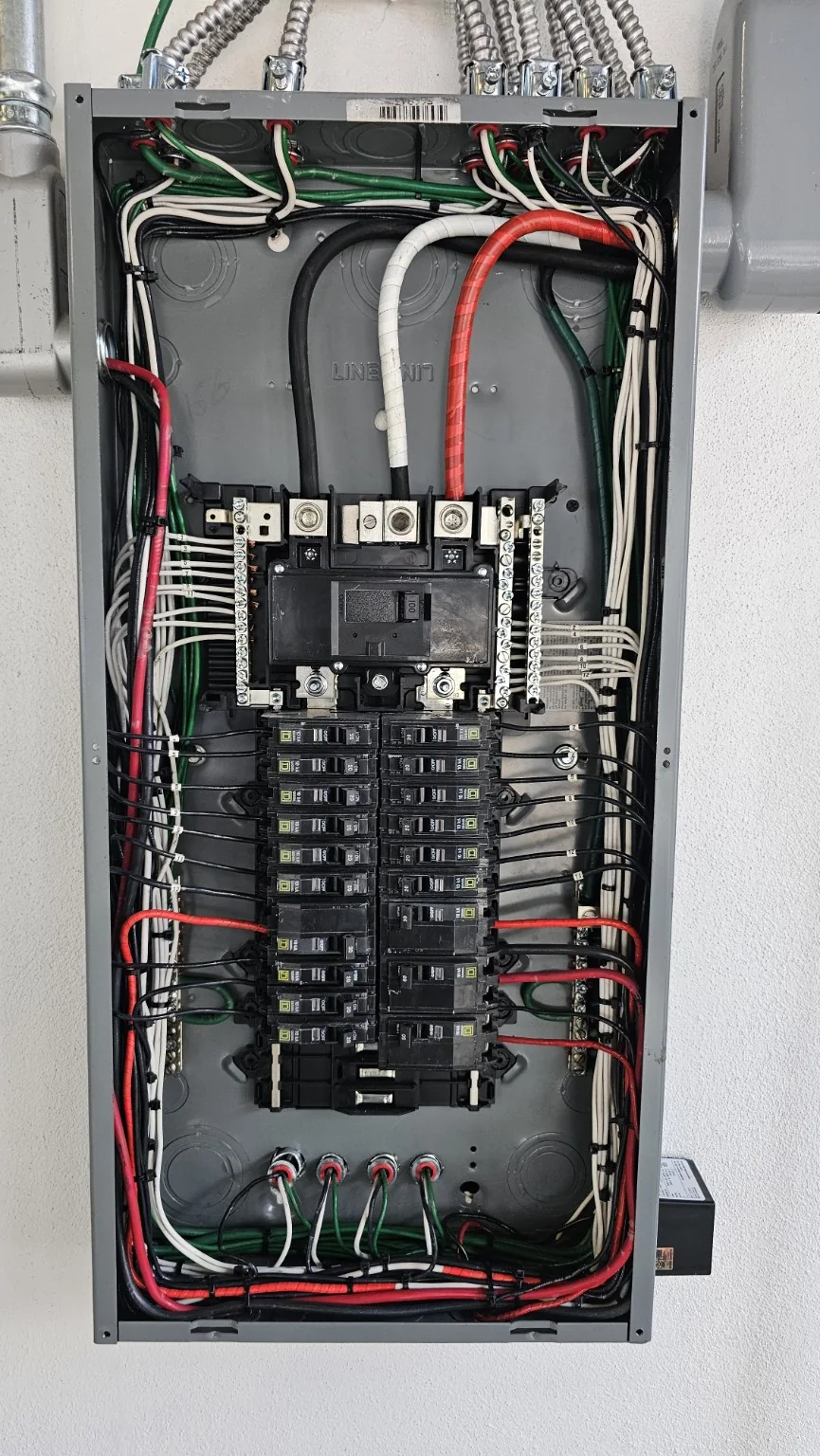Vista interior de un tablero eléctrico con interruptores y conductores organizados